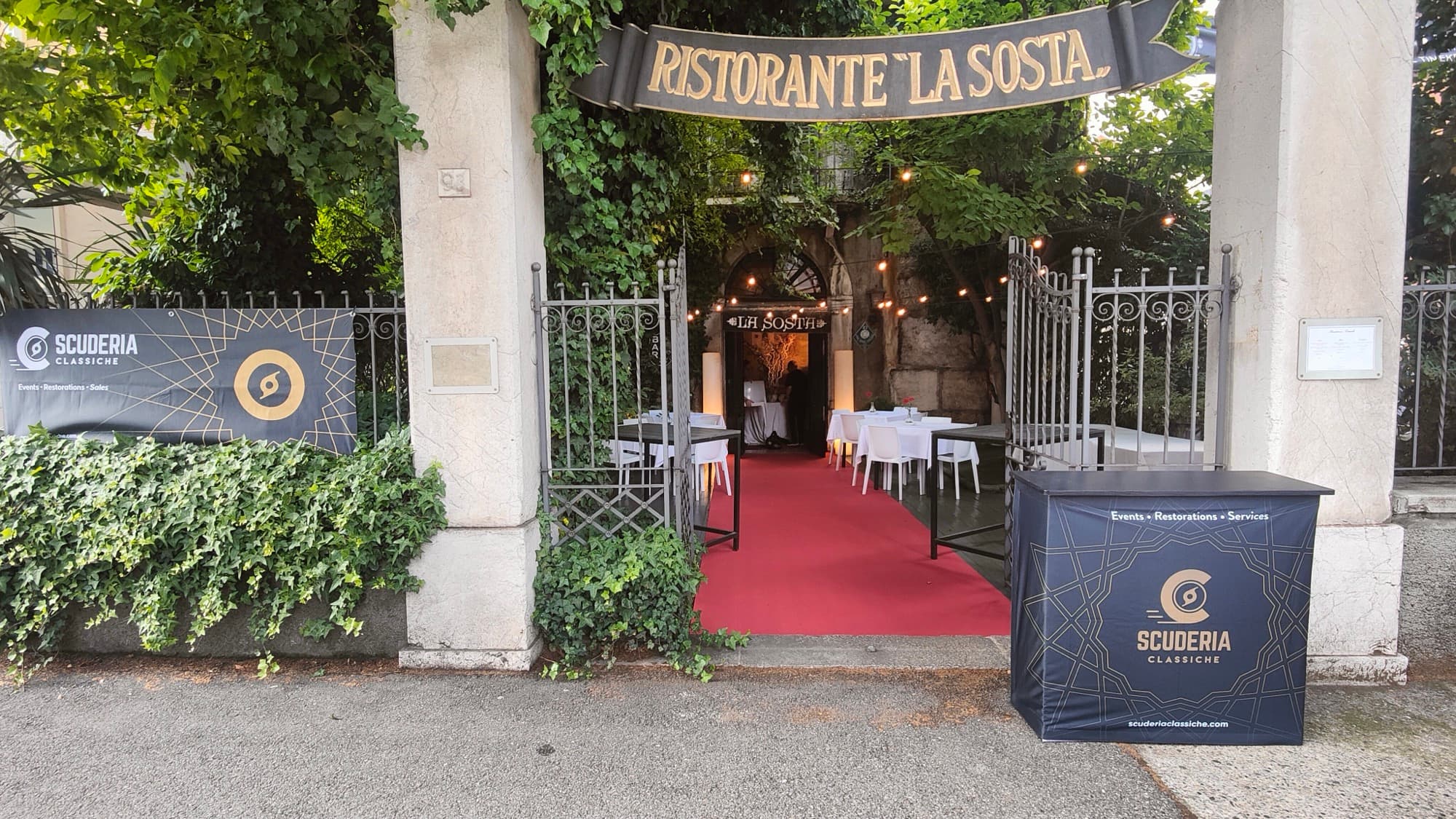 Ingresso del Ristorante La Sosta allestito per l'ospitalità Scuderia Classiche, tavoli con tovaglie bianche e tappeto rosso.