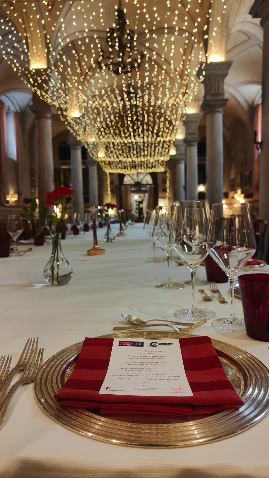 Tavolo di gala sotto un lampadario, con il menu 1000 Miglia · Scuderia Classiche sul piatto.